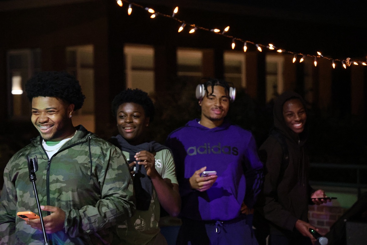 Four students laughing at an outdoor night event