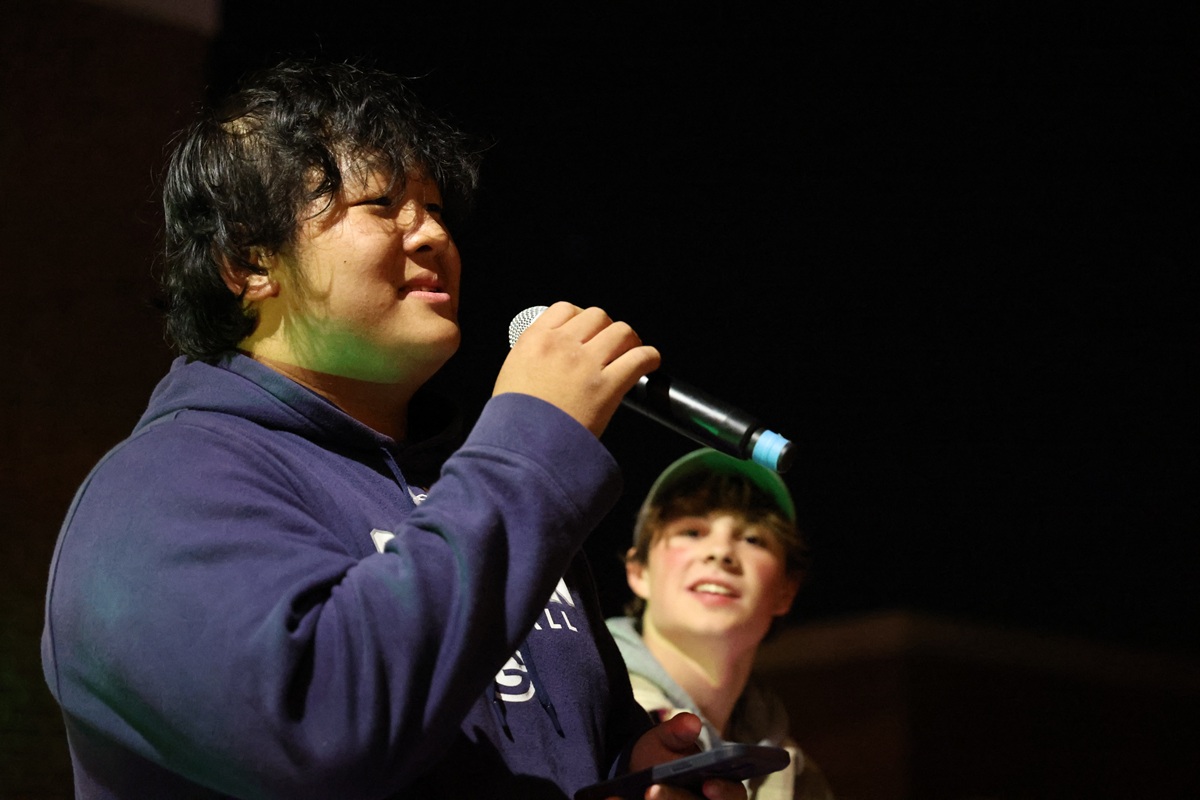 Student performing at open mic with stage lighting