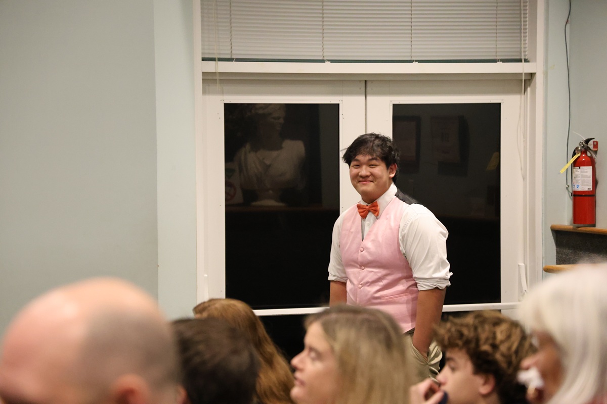 Student in pink vest and bow tie smiling at performance
