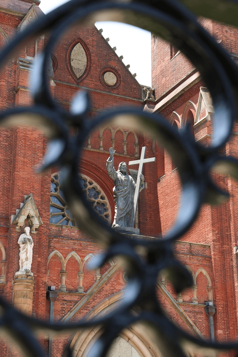 Cathedral statue of Christ seen through ornate iron gate
