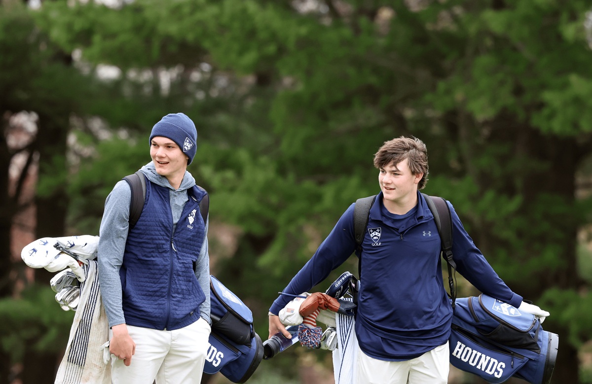 Two Gilman Hounds golfers walking with bags